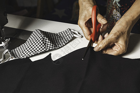 妇女用剪刀切割黑布 家庭工作和生活用品服装设计师职业材料手工衣服爱好女裁缝纺织品剪裁图片
