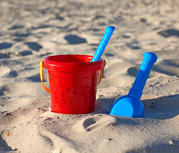 红色塑料桶和蓝色雷克 铲在沙子上旅行黄色塑料乐趣孩子海岸假期玩具游戏晴天图片