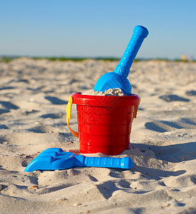红色塑料桶和蓝色雷克 铲在沙子上玩具孩子海岸乐趣塑料闲暇旅行黄色晴天海滩图片