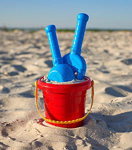 红色塑料桶和蓝色雷克 铲在沙子上假期孩子游戏塑料海岸黄色乐趣旅行玩具闲暇图片
