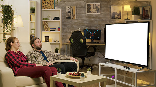 一对夫妇在沙发上放松 在电视上用绿色屏幕看电视客厅乐趣玩家享受男人微笑女士房子男性镜头图片