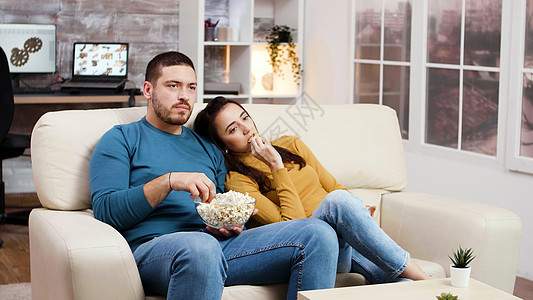 白种夫妇在客厅看电视放松着男人娱乐成人女士房子手表电视房间女性微笑图片