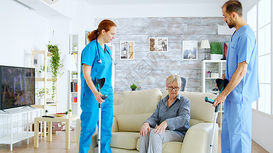 女医生及其助理帮助带拐杖的老妇人从沙发上站起来男人医疗疾病女性安慰退休照顾者社会护理轮椅图片