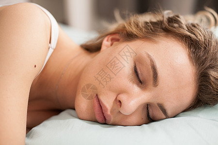 美丽的年轻姑娘睡在枕头上的头顶女孩女性女士眼睛幸福睡衣卧室白色房间说谎图片