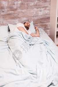 疲倦的男人睡在舒适的床上白色房间时间卧室睡眠枕头和平就寝男性成人图片