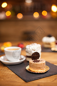 在美味的咖啡旁边的木桌上 在美味的甜点上放着巧克力碎屑 上面放着饼干特产专业蛋糕烹饪食物杏仁糕点饮食味道奶油图片