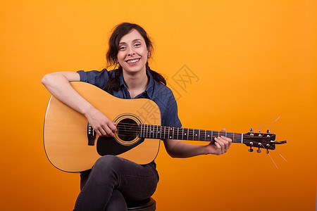 美丽的年轻女人的肖像 在演播室微笑 用吉他在黄色背景上艺术家女孩艺术喜悦女性音乐头发乐器乐趣姿势图片