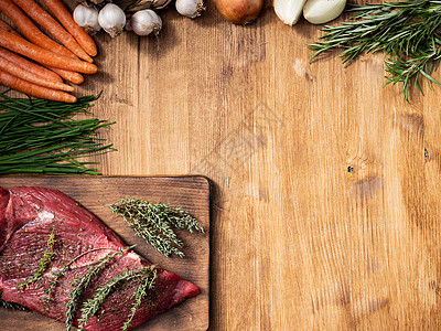 切菜板上红肉的顶端视图 绿边旁有迷迭香背景图片