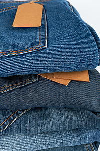 白色背景上折叠的蓝色牛仔裤棉布棕色销售牛仔布纺织品裤子衣服购物标签工作室图片