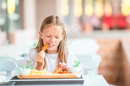 可爱的小女孩在户外咖啡厅吃晚饭童年孩子晚餐食物勺子面条婴儿餐厅盘子咖啡店图片