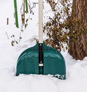 从一堆雪堆中挖出塑料绿色铲子白色季节降雪工具天气车道背景图片