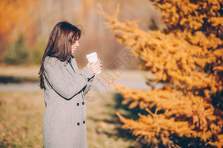 秋瀑概念  美丽的女人在秋公园喝咖啡 在秋天的树叶下金发女郎森林享受女性冒充头发女士叶子女孩季节图片