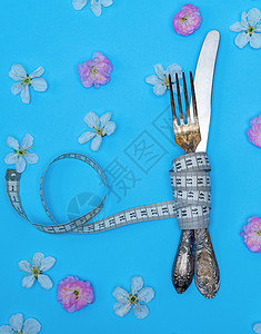 用测量胶带包裹的铁叉和刀食物银器白色概念磁带重量刀具饮食损失蓝色图片