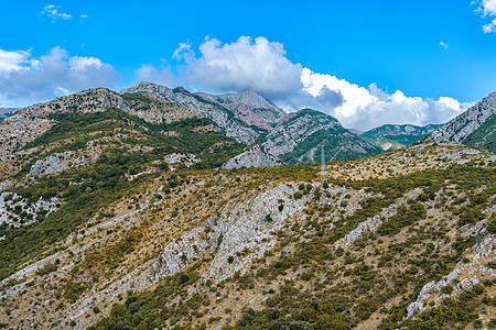 覆盖着青蓝天空植被的山坡和山峰 以及风景岩石石头全景旅行植物蓝色旅游顶峰森林图片