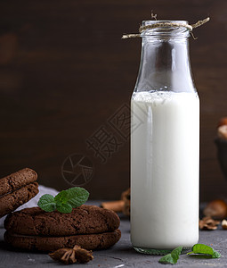 装满牛奶的全玻璃瓶圆形巧克力饮料饼干桌子早餐玻璃棕色食物奶制品图片
