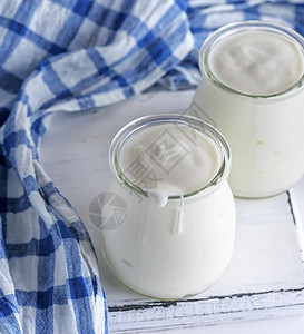 白木板上带自制酸奶的玻璃罐桌子牛奶白色木头奶油早餐餐巾蓝色营养奶制品图片