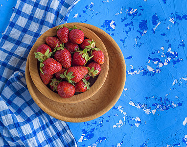 棕色木制圆板上鲜熟的红草莓盘子食物桌子团体红色浆果季节蓝色水果甜点图片