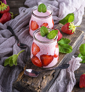 玻璃罐中新鲜草莓和酸奶的清凉水果绿色浆果甜点勺子饮料桌子牛奶饮食果汁图片