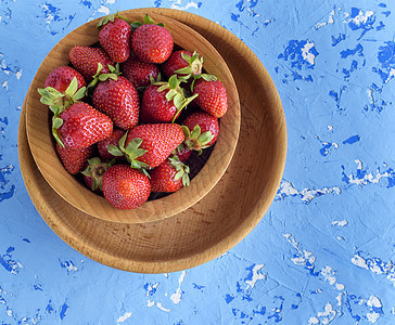 棕色木制圆板上鲜熟的红草莓甜点水果盘子季节食物蓝色红色浆果团体桌子图片