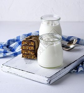 在玻璃罐子和零食中自制酸奶桌子木板蓝色勺子牛奶营养奶油饮食餐巾奶制品图片