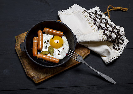 黑煎锅里的炸鸡蛋和香肠图片
