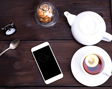 黑茶加柠檬 在圆圆白陶瓷杯中早餐饼干技术咖啡店食物盘子勺子液体饮料触摸屏图片