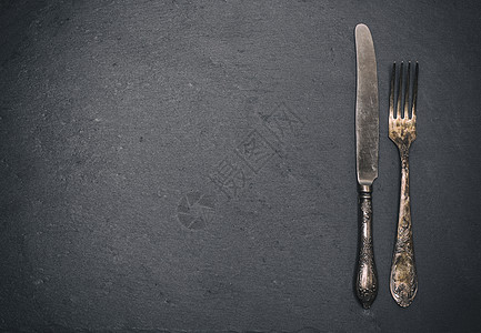 黑色背景的古老铁叉和刀空间用餐桌子风格食物古董用具服务银器装饰图片