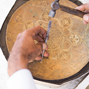 老工匠工作时的铜追逐者精神男人黄铜用具工人装饰品凿子手工雕刻师托盘背景