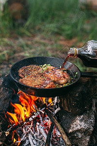 篝火派对与红菜一起在露天着火的锅里煎肉 将牛排放在锅里牛肉油炸燃烧迷迭香食物鱼片木炭派对午餐香料背景