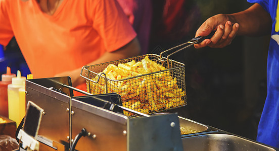 员工用热油炸炸薯条 卖食物在图片