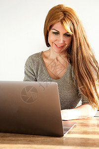 从事膝上型电脑工作的有吸引力的成年妇女桌子生活女性笔记本微笑女士互联网商业技术办公室图片