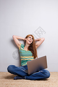 妇女用笔记本电脑在地板上放松图片