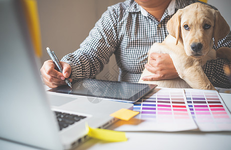设计师和设计师在家里工作 通过携带小狗在染色职业药片技术艺术办公室猎犬工作室卡片调色板图片