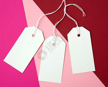 在彩色背面的绳索上贴三个白色白纸长方形标签折扣空白粉色生日邀请函价钱卡片纸板回收细绳图片