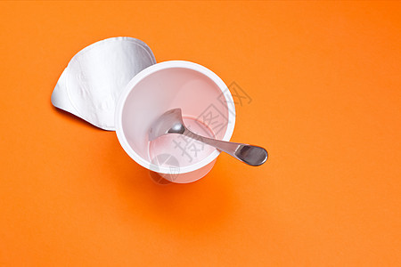 橙色背景的勺子空清酸奶杯橙子厨房塑料奶制品白色早餐薄片饮食牛奶奶油图片