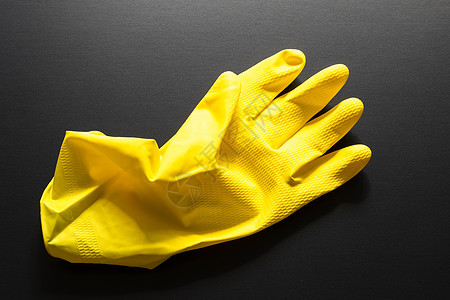 在黑色背景上隔离的黄色橡胶手套用具打扫橡皮手指图片