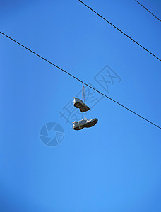 旧鞋挂在一条电线上 对着蓝天恶作剧家庭力量绳索鞋类蕾丝蓝色自由电缆吊索图片