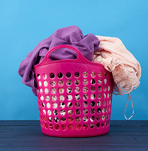 粉红色塑料篮 装满了衣服和蓝色背面的衬布衬衫家庭粉色浴室纺织品洗涤洗衣店织物贮存盒子图片