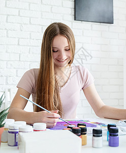 微笑着的女艺术家在她工作室衣服上绘画图片