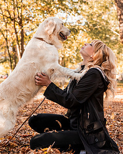 一个美丽的女人 带着她的拉布拉多猎犬 躺在公园里友谊宠物乐趣犬类成人女孩树叶朋友女性拥抱图片