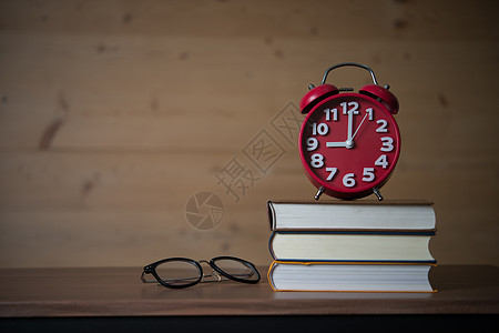 9点9点在一堆书上闹钟 木板上有眼镜休息时间警报艺术创造力学习桌子圆圈杯子图片