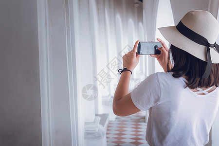 旅游妇女在寺庙观光艺术建筑时享受乐趣 旅行者亚洲妇女的肖像正在精神场所参观和拍摄佛陀故事的美术画背景图片