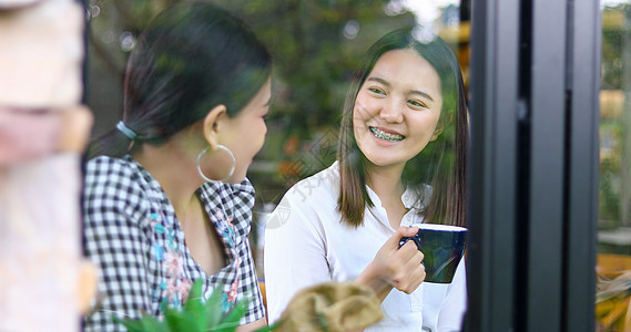 两个亚裔妇女喝咖啡 和两个开心愉快的女人 在闲聊女孩讨论快乐闲暇食物桌子幸福朋友们咖啡女孩们图片