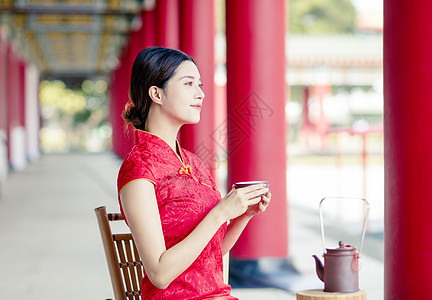 穿旧中国传统服装的亚洲美女 喝水i宗教桌子茶壶女士旗袍寺庙杯子戏服旅行裙子图片