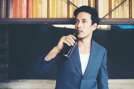 英俊的年轻商务人士在外面喝啤酒白色瓶子男性男人饮料成人酒精图片