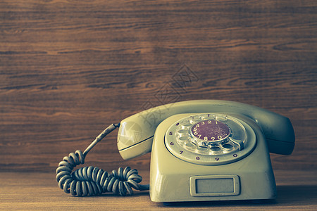 木桌背景上的旧电话 复古吨数字拨号桌子耳机旋转绳索铃声电缆器具讲话图片