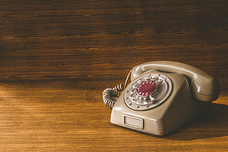 在木桌背景的老电话讲话铃声器具电缆塑料技术耳机旋转数字拨号图片
