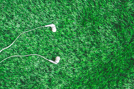 绿色草原上耳机的顶端视图立体声音乐工具收音机笔记草地技术场地白色派对背景图片