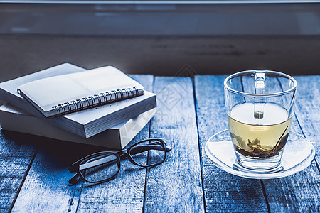 杯茶 木制桌上有书和眼镜桌子飞碟玻璃杯子蓝色笔记本时间图片