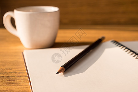 木桌背景上有铅笔和咖啡杯的空白笔记本 选择性聚焦图片